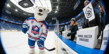Wenn Profis zusammenarbeiten: Warum die neue Partnerschaft zwischen den Eisbären Berlin und dem Tierheim Berlin ein Signal gegen Tierrechts-Propaganda ist 22 Ein Eisbär in Eishockey-Ausrüstung der Berliner Eisbären steht in einem Stadion neben Fans, die Spenden für das Tierheim sammeln – Darstellung der Partnerschaft Eisbären Berlin Tierheim.