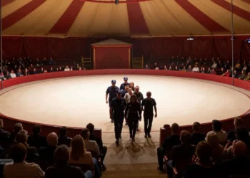 Sicherheitskräfte führen Störer aus der hell erleuchteten Manege, während Zuschauer im Hintergrund reagieren und der Circus Krone Protest sichtbar beendet wird