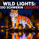 KI-generiertes Symbolbild. Eine leuchtende Tier-Skulptur bei den Wild Lights im Zoo Schwerin in einer nächtlichen Parklandschaft.