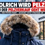 Woolrich wird pelzfrei: Winterparka mit Pelzbesatz vor einem Woolrich-Geschäft. Trotz Pelzausstieg ab 2027 dürfen Restbestände weiterverkauft werden.